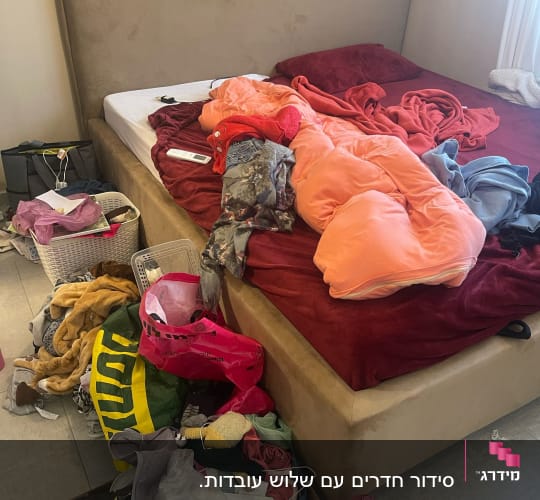 בגדים מפוזרים על מיטה וארגזים על הרצפה